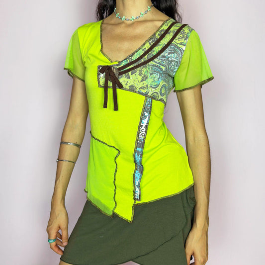 This vintage 2000s lime green top features an asymmetric patchwork design with aqua and brown print accents, a deep V-neckline with ribbon bow detail, contrast overlock seams, short semi-sheer mesh sleeves and a fitted cut. A bold, deconstructed piece that plays with color and form, ideal for summer looks. Made from a viscose and elastane blend. Excellent vintage condition.