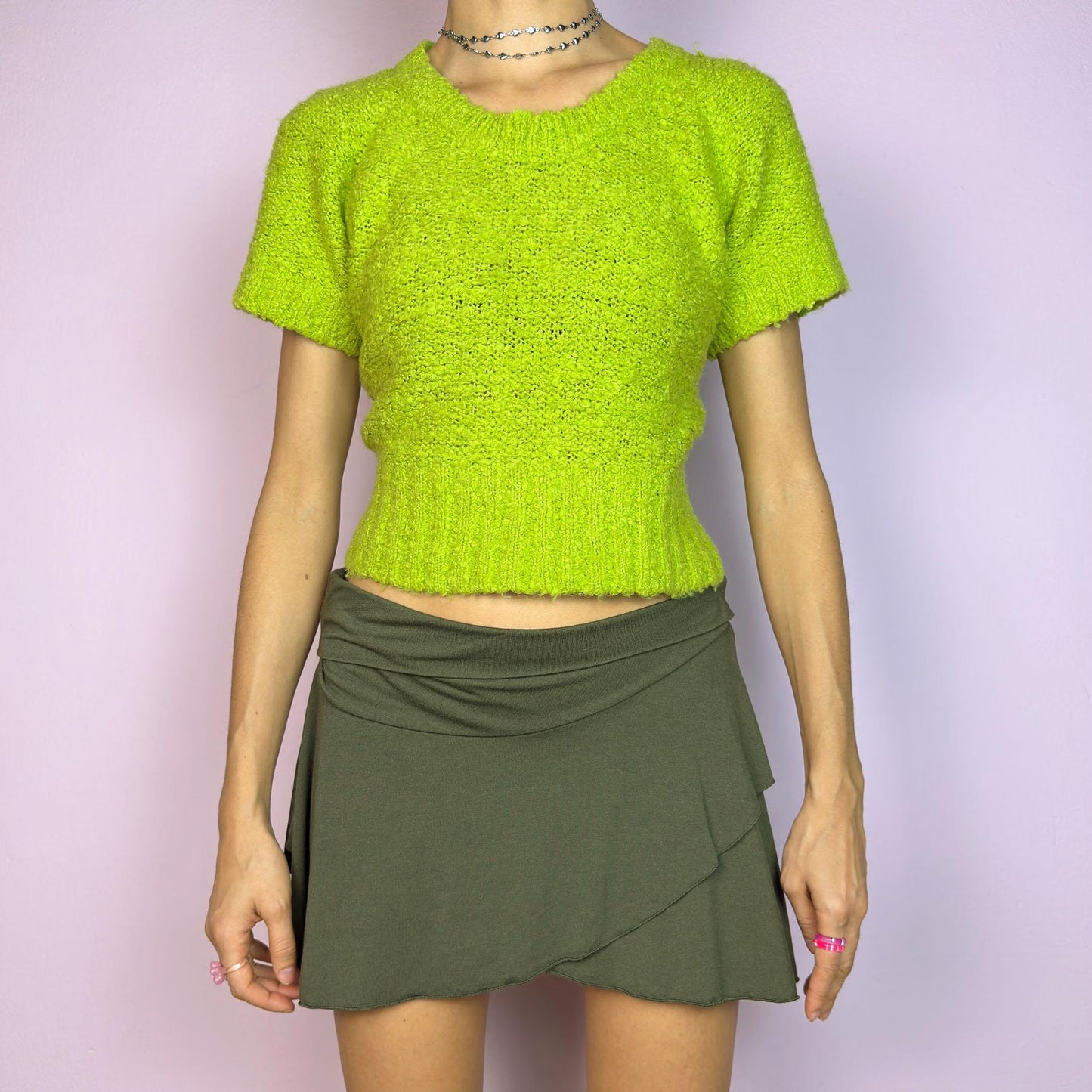 The Y2K Green Knitted Top is a vibrant vintage 2000s piece featuring a lime-green hue. Designed with a cropped silhouette, short sleeves, and a stretchy ribbed hem, this knit top adds a playful touch to casual outfits. Perfect for brightening up your spring or summer wardrobe. Great vintage condition.