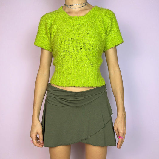 The Y2K Green Knitted Top is a vibrant vintage 2000s piece featuring a lime-green hue. Designed with a cropped silhouette, short sleeves, and a stretchy ribbed hem, this knit top adds a playful touch to casual outfits. Perfect for brightening up your spring or summer wardrobe. Great vintage condition.