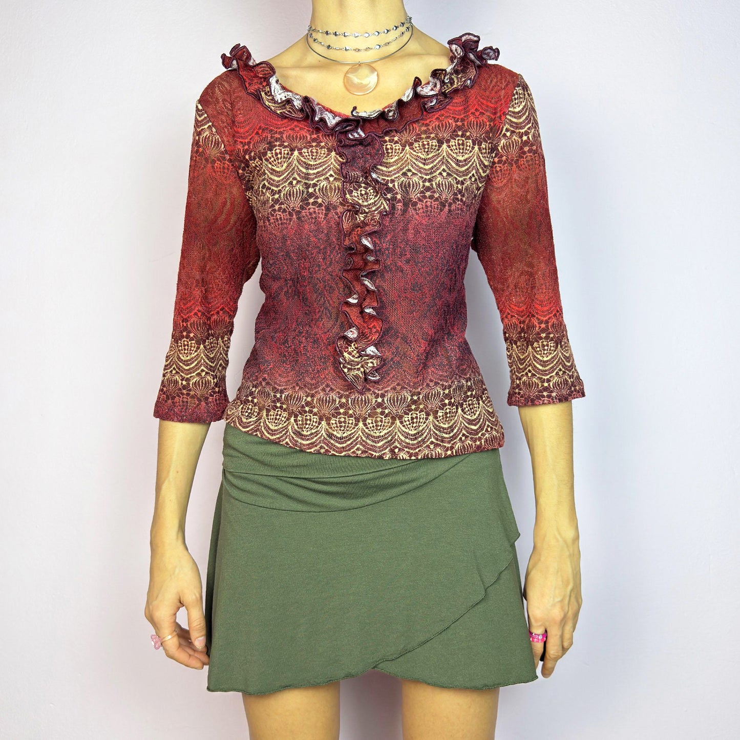 The Y2K Maroon Ruffle Mesh Top is a romantic vintage 2000s piece. Featuring a semi-sheer lace-inspired design in warm red tones, it showcases intricate patterns complemented by a ruffled neckline and 3/4 sleeves. Perfect for chic evening wear or adding a touch of whimsy to a casual outfit. Great vintage condition.