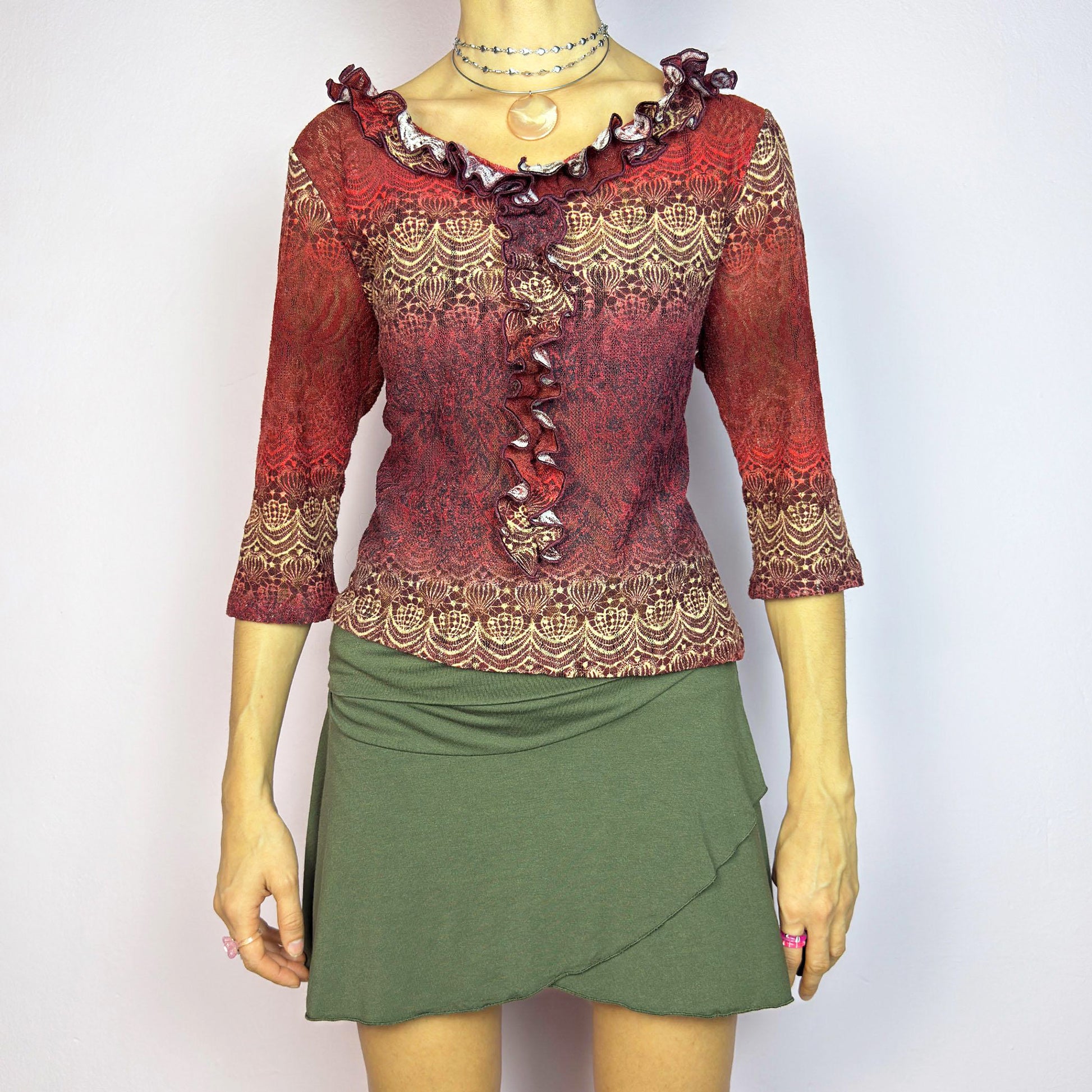 The Y2K Maroon Ruffle Mesh Top is a romantic vintage 2000s piece. Featuring a semi-sheer lace-inspired design in warm red tones, it showcases intricate patterns complemented by a ruffled neckline and 3/4 sleeves. Perfect for chic evening wear or adding a touch of whimsy to a casual outfit. Great vintage condition.