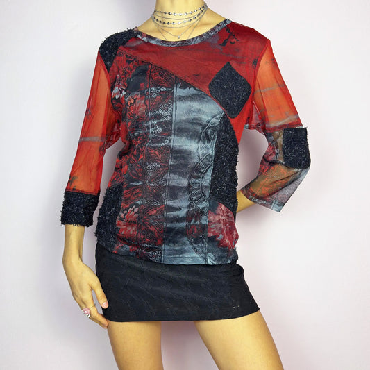 The Y2K Patchwork Print Mesh Top is a vintage 2000s statement piece featuring a semi-sheer patchwork design with a mix of mesh, printed fabric, and textured appliqué details. Designed with a round neckline, 3/4 length sleeves, and contrast fabric patches, this edgy top is perfect for alternative, cyber, or grunge-inspired outfits. Excellent vintage condition.