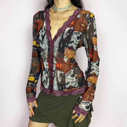 The vintage 2000s mesh sheer blouse features an abstract painting print in burnt orange, ochre, red, and charcoal. Made of stretch polyester mesh, it has long sleeves, a deep V-neckline trimmed in plum lace, and a tonal button front. This top is a rare avant garde piece with a romantic, artsy edge—perfect for chic events, layering, and transitional weather. Excellent vintage condition.