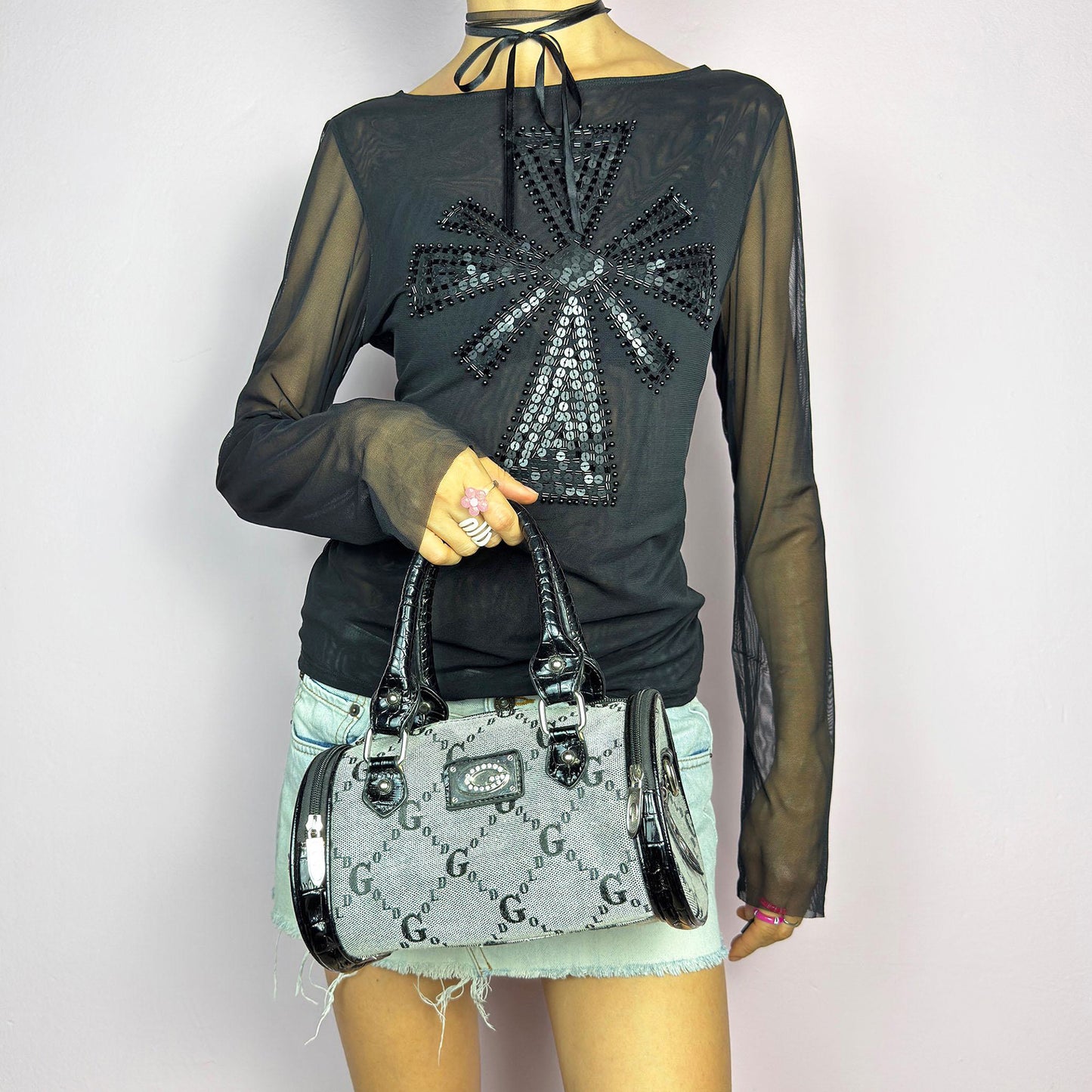 The Y2K Monogram Mini Duffel Bag is a stylish vintage 2000s accessory. Featuring a structured silhouette with an all-over monogram print, sleek black faux patent leather accents, and silver hardware. It includes dual top handles, a detachable shoulder strap for versatile carrying options, and multiple zip compartments. The cylindrical shape and compact size make it perfect for day-to-night use. Great vintage condition.