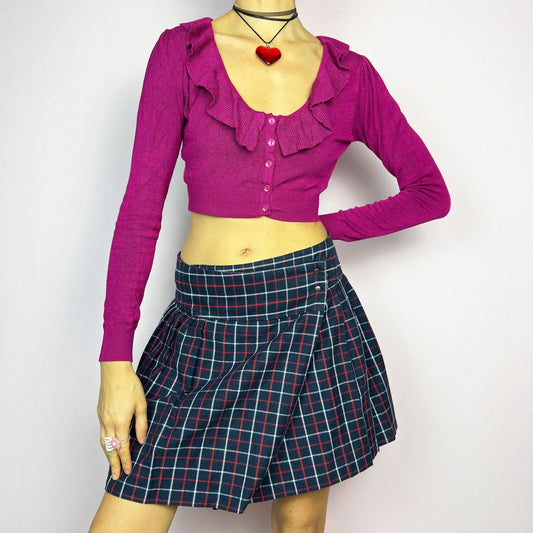 The Y2K Plaid Pleated Wrap Mini Skirt is a vintage 2000s piece featuring a wrap-style waistband with snap button details. Made from a plaid fabric in navy blue tones, it has structured pleats that create a classic silhouette, perfect for preppy or casual outfits.