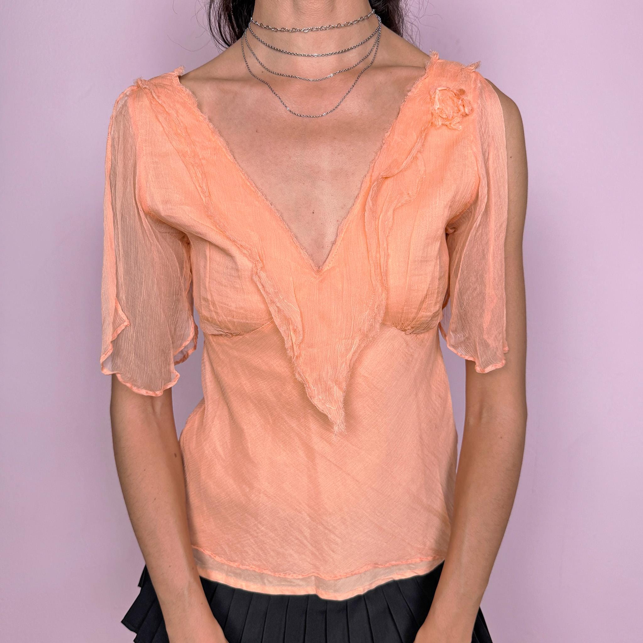 Vintage 2000s pastel light orange-peach fitted top with a deep V-neck, side zip closure, and semi-sheer split flutter sleeves. Romantic, flowy, ethereal design with a soft crinkle texture and a small shoulder rosette, ideal for dreamy summer events or formal looks. Made with a 100% cotton lining and a 100% viscose outer layer. Excellent vintage condition.