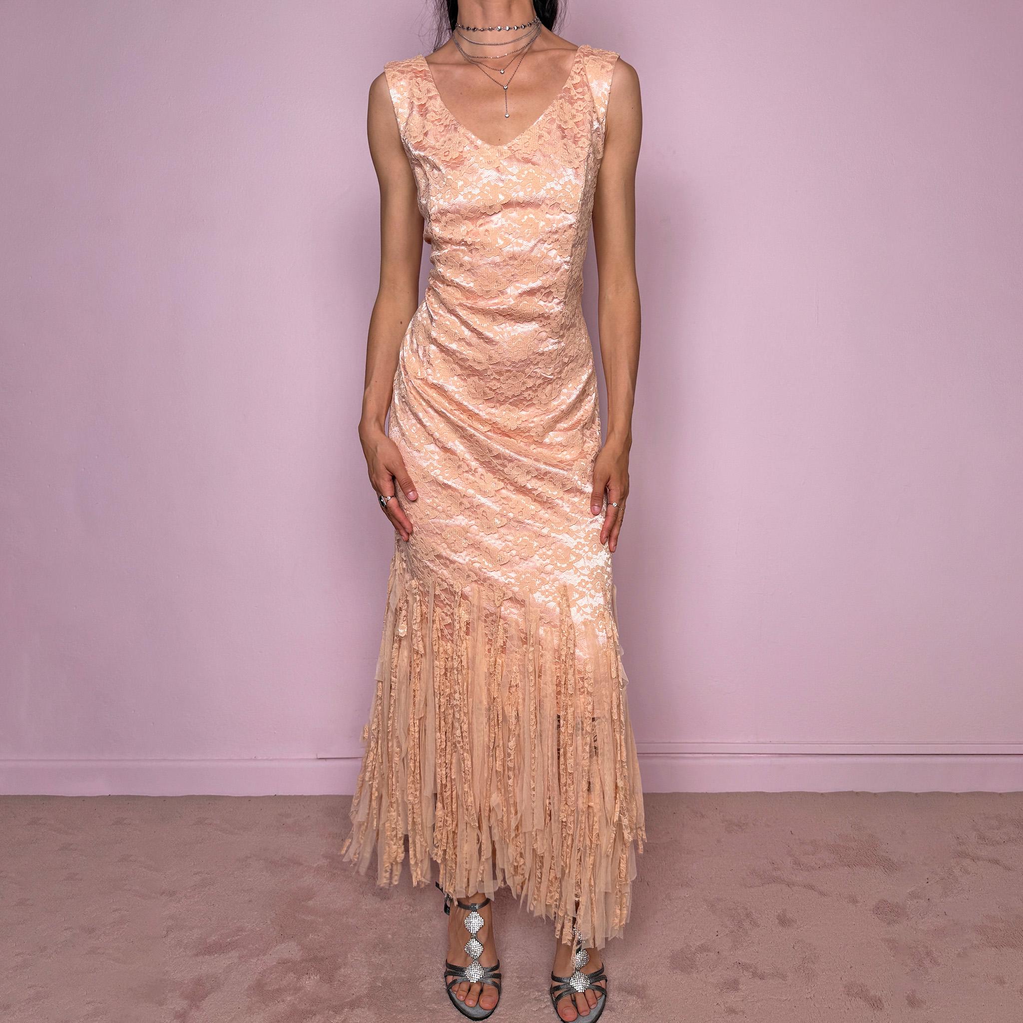 Vintage 2000s pastel peach lace maxi dress. Features a romantic V-neckline, fitted sleeveless silhouette, side zip closure, and a dramatic fringed lace hem. A refined occasion dress in a soft peach, salmon, and blush pink tone, perfect for romantic evening styling, spring-summer events, weddings, or elevated vintage looks. Made in Spain by a Spanish designer, with a nylon-cotton blend outer layer and polyester lining, with no stretch. Excellent vintage condition.