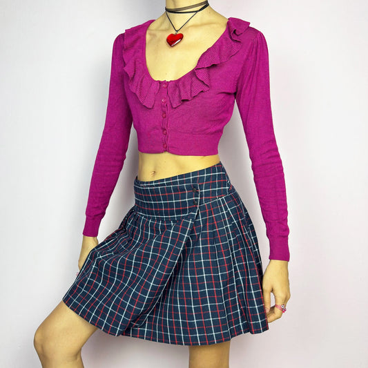 The Y2K Plaid Pleated Wrap Mini Skirt is a vintage 2000s piece featuring a wrap-style waistband with snap button details. Made from a plaid fabric in navy blue tones, it has structured pleats that create a classic silhouette, perfect for preppy or casual outfits. Great vintage condition.