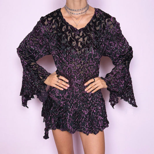 This vintage 2000s purple and black devoré velvet top delivers a dark romantic, witchy, goth aesthetic with a fitted bodice, sheer burnout pattern, metallic threads, asymmetric bell sleeves, and a flared hem. Ideal for evening styling, festivals, and statement layering. An archival French piece with a stretchy finish for comfortable wear. Excellent vintage condition.