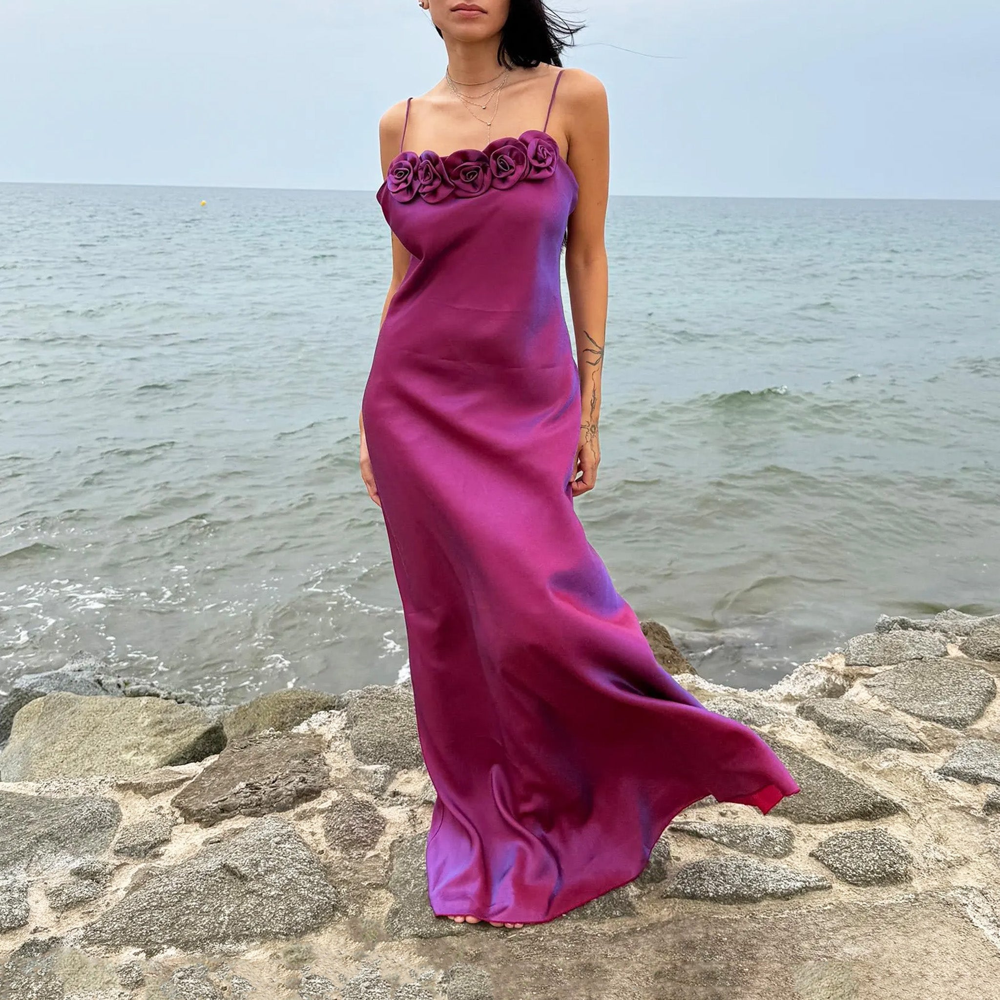 Vintage 2000s iridescent slip midi dress in a maroon/purple tone with blueish undertones that shift in the light. Features spaghetti straps and a sculptural rosette appliqué along the bust, with red carpet appeal for proms, summer weddings, gala events, or romantic evenings. Made in France from a non-stretch polyester viscose blend. Great vintage condition.
