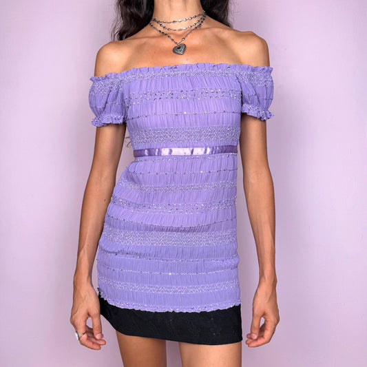 This vintage 2000s Victoria’s Secret off-shoulder top features a romantic ruched pleated design in soft lavender purple. Detailed with short sleeves, a satin tie-back waist, and a feminine fitted silhouette, it channels dreamy Y2K energy perfect for summer nights, date looks, or ethereal layering. A collectible archive piece with delicate texture and sensual elegance. Made from a polyester stretch blend. Excellent vintage condition.