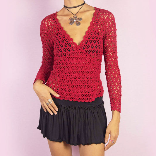 The Y2K Red Crochet Wrap Cardigan is a vintage 2000s piece featuring a romantic deep V-neckline with an intricate open-knit design. Its wrap style and tie closure at the back form a stylish bow, creating a flattering silhouette. Perfect for layering in spring and summer.