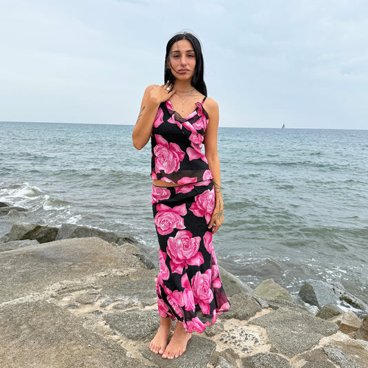 This vintage 2000s two-piece set features a pleated black fabric with oversized pink rose print. The trumpet godet midi skirt with elastic waist pairs with a cami top detailed by a ruffled neckline. A romantic feminine coord, ideal for summer promenades, Mediterranean cruises, or sunset parties. A collectible statement in girly Y2K style. Made in France from a polyester blend. Excellent vintage condition.