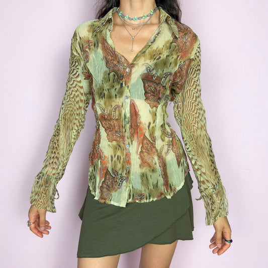 This vintage 2000s pleated sheer blouse blends soft sage green with wild paisley and animal-inspired prints in rust and brown. Features include tie details at the flared cuffs and a sharp pointed collar. A lightweight, breathable layer ideal for transitional styling, evening events, or a creative summer escapade in the Mediterranean. A rare, print-rich piece channeling bohemian and surrealist textures. Excellent vintage condition.