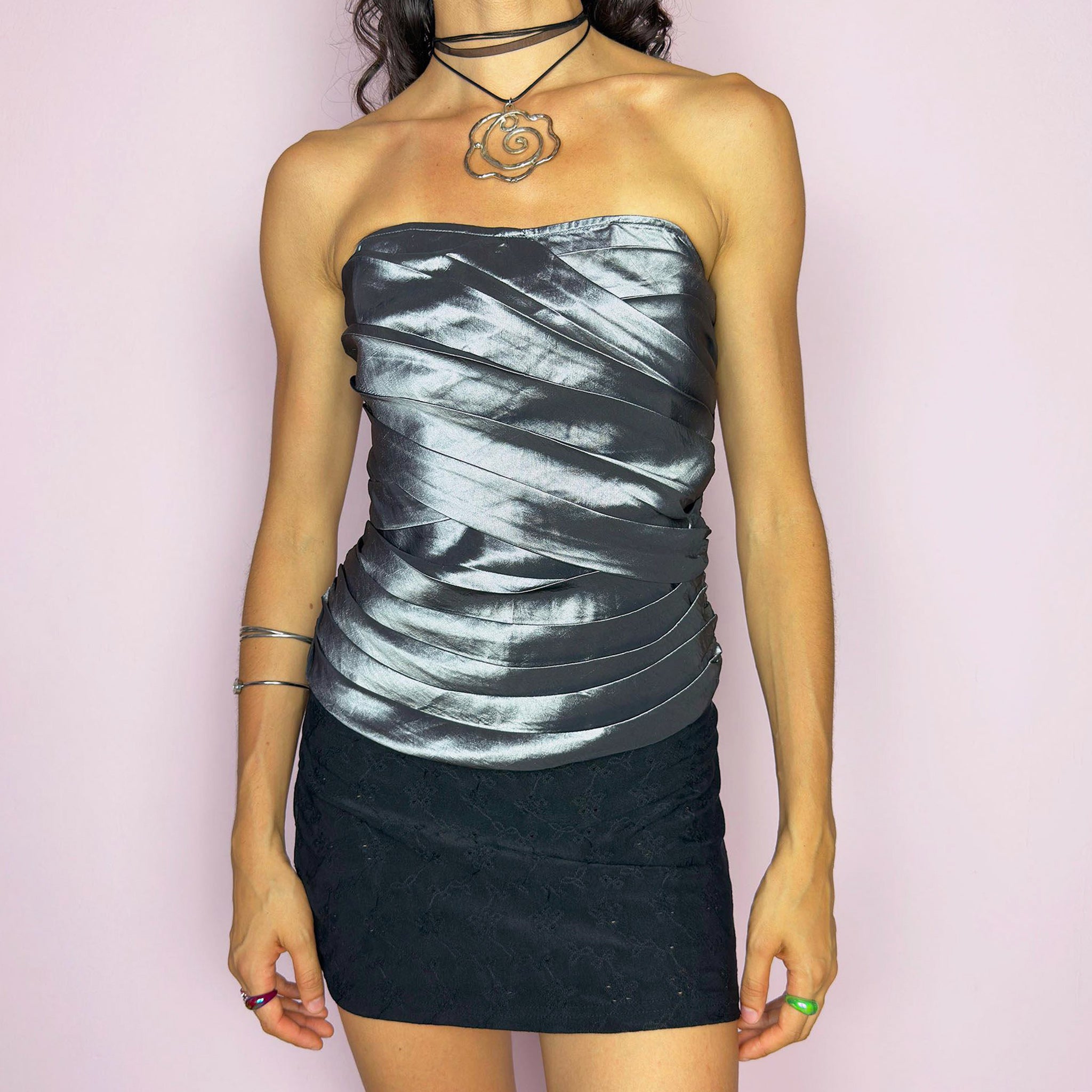 This vintage 2000s silver corset top features sculptural pleated draping over a glossy metallic base with internal boning and a back zipper closure. The strapless fit hugs the body in a sleek, structured silhouette, perfect for formal events, prom nights, or modern wedding styling. A rare Y2K statement piece with futuristic glam and dramatic polish, elevated yet bold, with impeccable shape and shine. Excellent vintage condition.