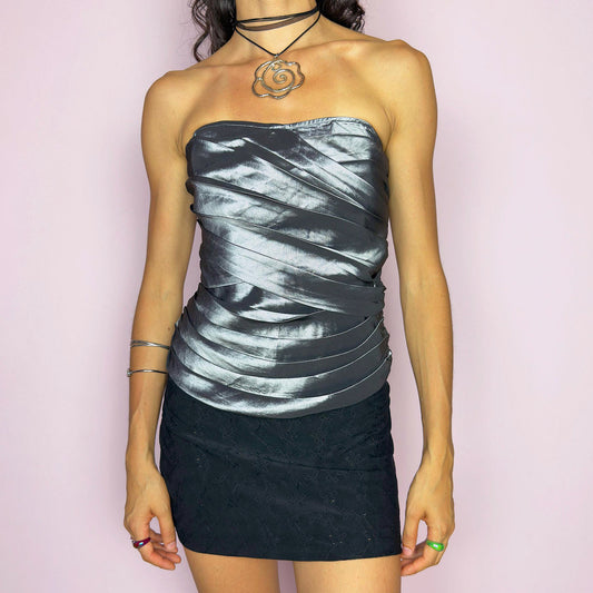 This vintage 2000s silver corset top features sculptural pleated draping over a glossy metallic base with internal boning and a back zipper closure. The strapless fit hugs the body in a sleek, structured silhouette, perfect for formal events, prom nights, or modern wedding styling. A rare Y2K statement piece with futuristic glam and dramatic polish, elevated yet bold, with impeccable shape and shine. Excellent vintage condition.