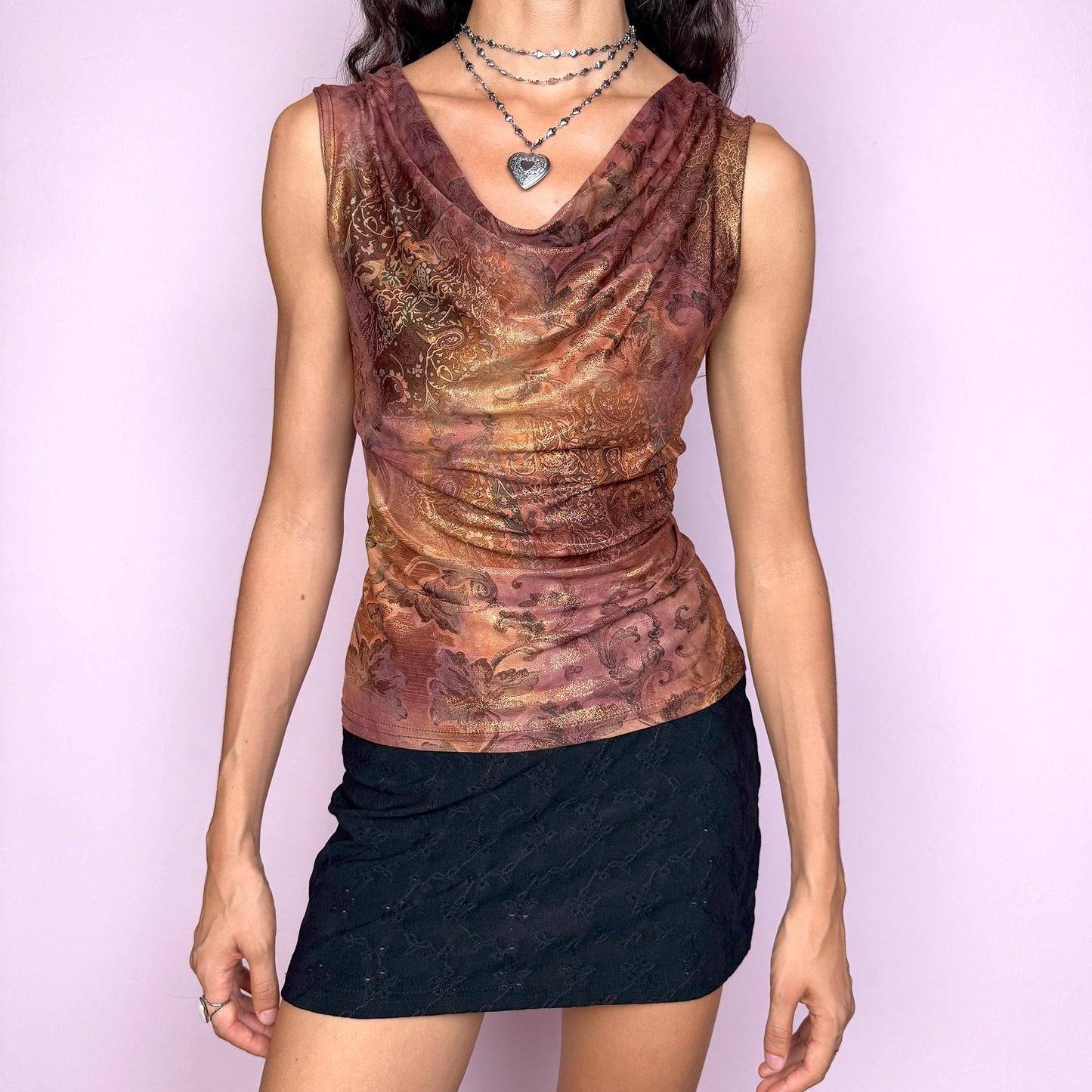 This vintage 2000s sleeveless cowl neck top features a shimmering floral-paisley print in rich, flattering warm bronze, copper, and burgundy tones. The stretchy fabric drapes beautifully, creating a spotlight-ready silhouette ideal for summer nights, parties, or elevated Y2K styling. A collectible archive piece blending romantic detail with glamorous edge. Made from a polyester stretch blend. Made in France. Excellent vintage condition.