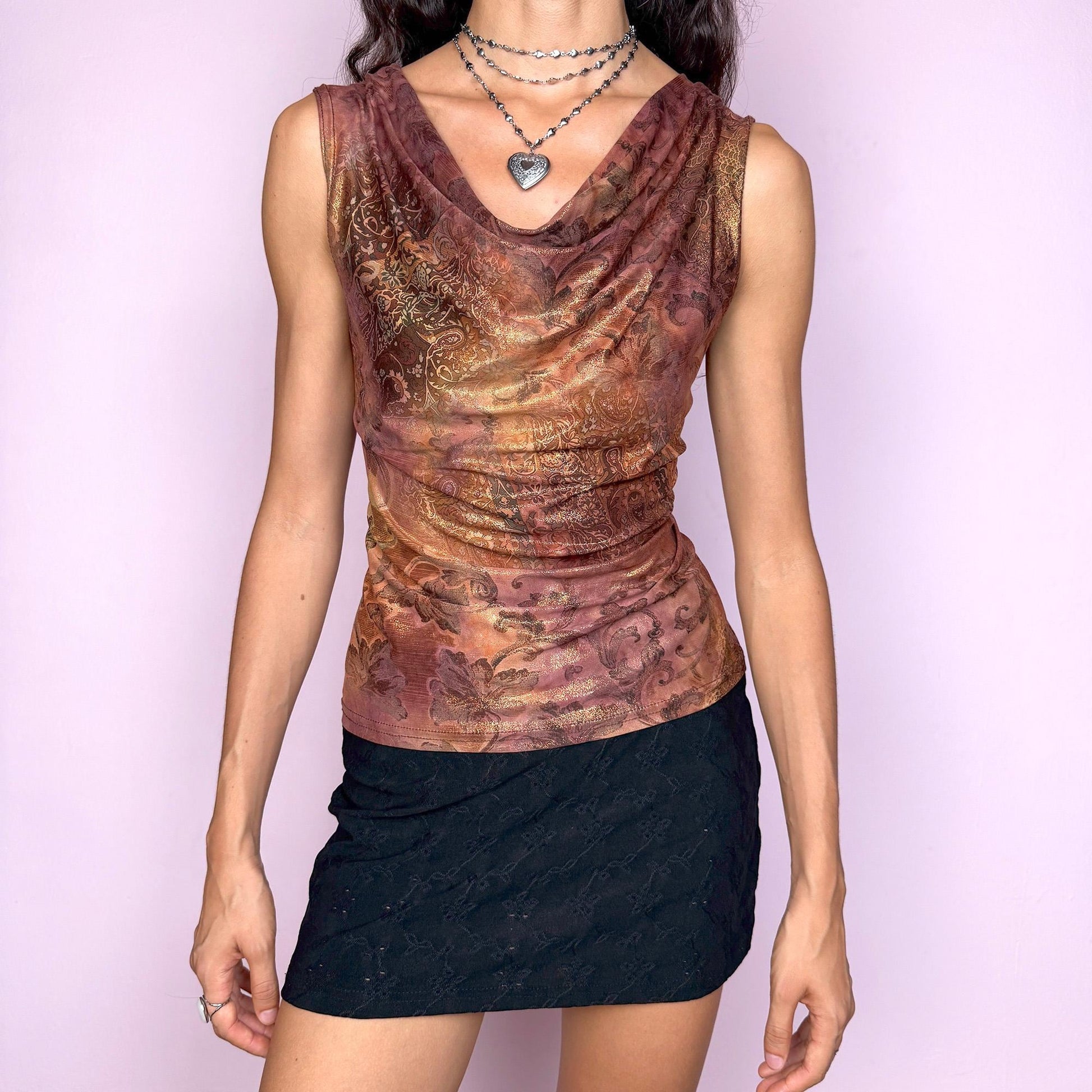 This vintage 2000s sleeveless cowl neck top features a shimmering floral-paisley print in rich, flattering warm bronze, copper, and burgundy tones. The stretchy fabric drapes beautifully, creating a spotlight-ready silhouette ideal for summer nights, parties, or elevated Y2K styling. A collectible archive piece blending romantic detail with glamorous edge. Made from a polyester stretch blend. Made in France. Excellent vintage condition.