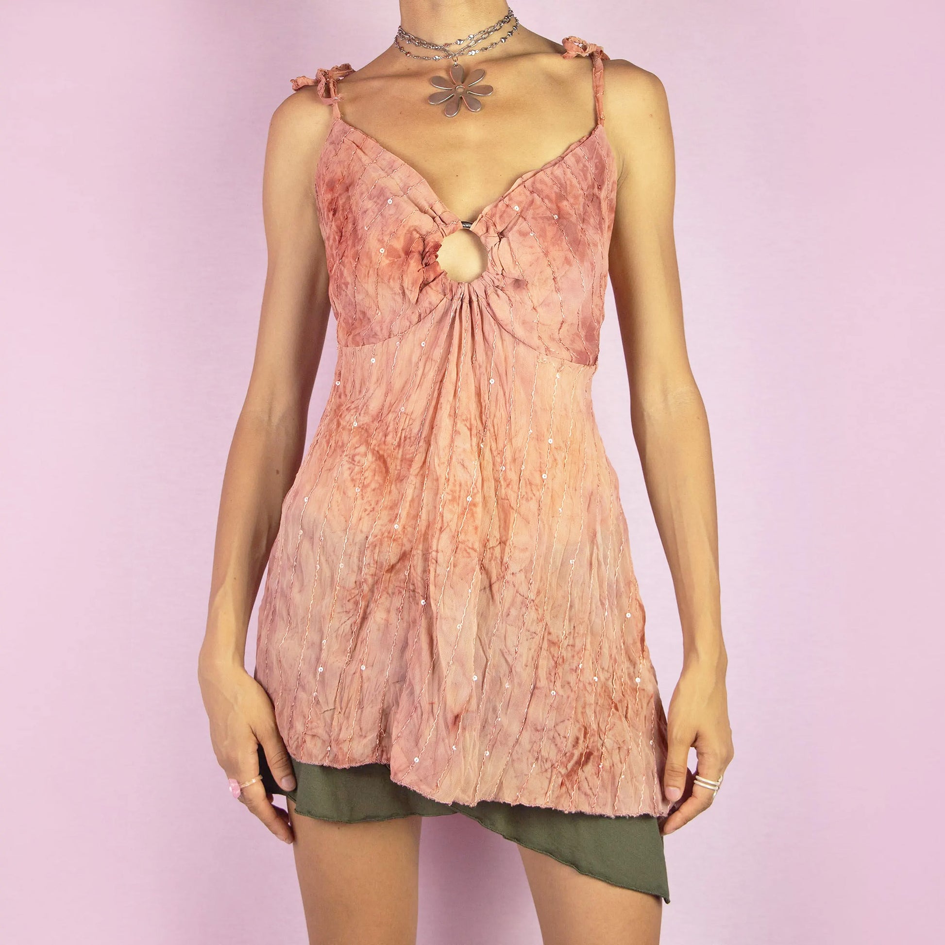 The Y2K Tie Dye Flowy Top is a vintage 2000s boho-inspired piece featuring a soft terracotta tie-dye pattern, delicate sequin embellishments, and a flattering keyhole front detail. Designed with adjustable shoulder ties and a flowing silhouette, it also features an asymmetrical pointed hem, making it perfect for summer festivals or relaxed casual outings.