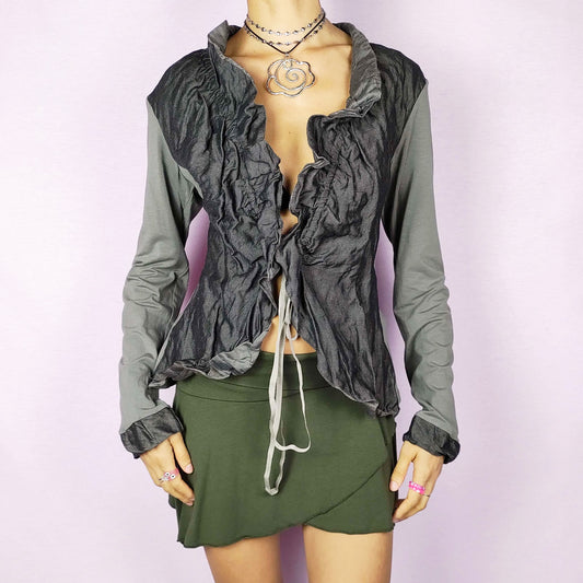 The Y2K Ruffle Tie Front Top is a vintage 2000s khaki-green grayish elegant and formal bolero jacket featuring a unique crinkled texture, ruffled details along the front and an adjustable tie closure. Perfect for both office wear and evening events.