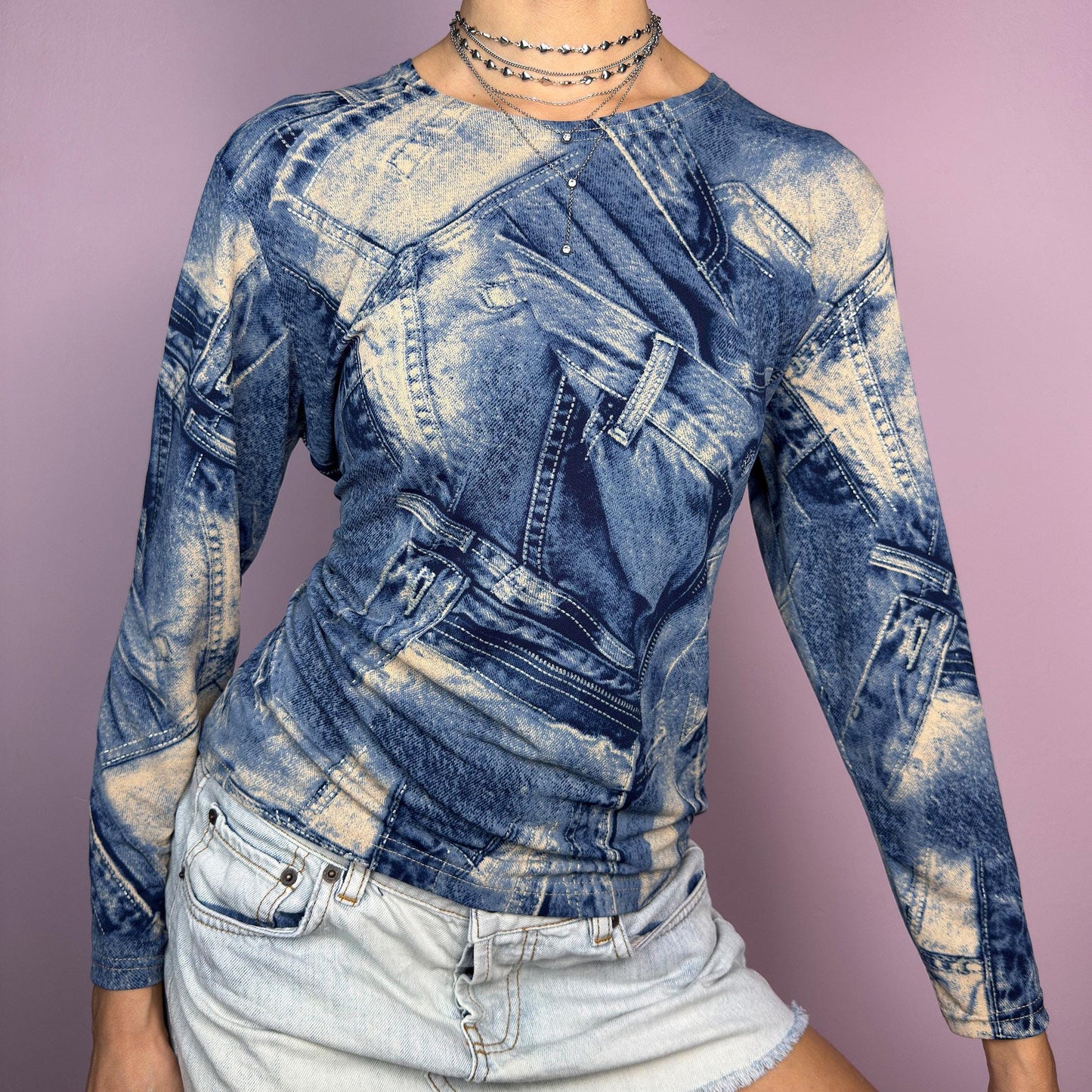 The Y2K Denim Printed Top is a vintage 2000s piece featuring an all-over trompe-l&#39;œil denim print on a stretchy fabric. Designed with long sleeves and a fitted silhouette, this statement top blends classic denim aesthetics with a futuristic vibe. Perfect for casual outfits. adult world shop