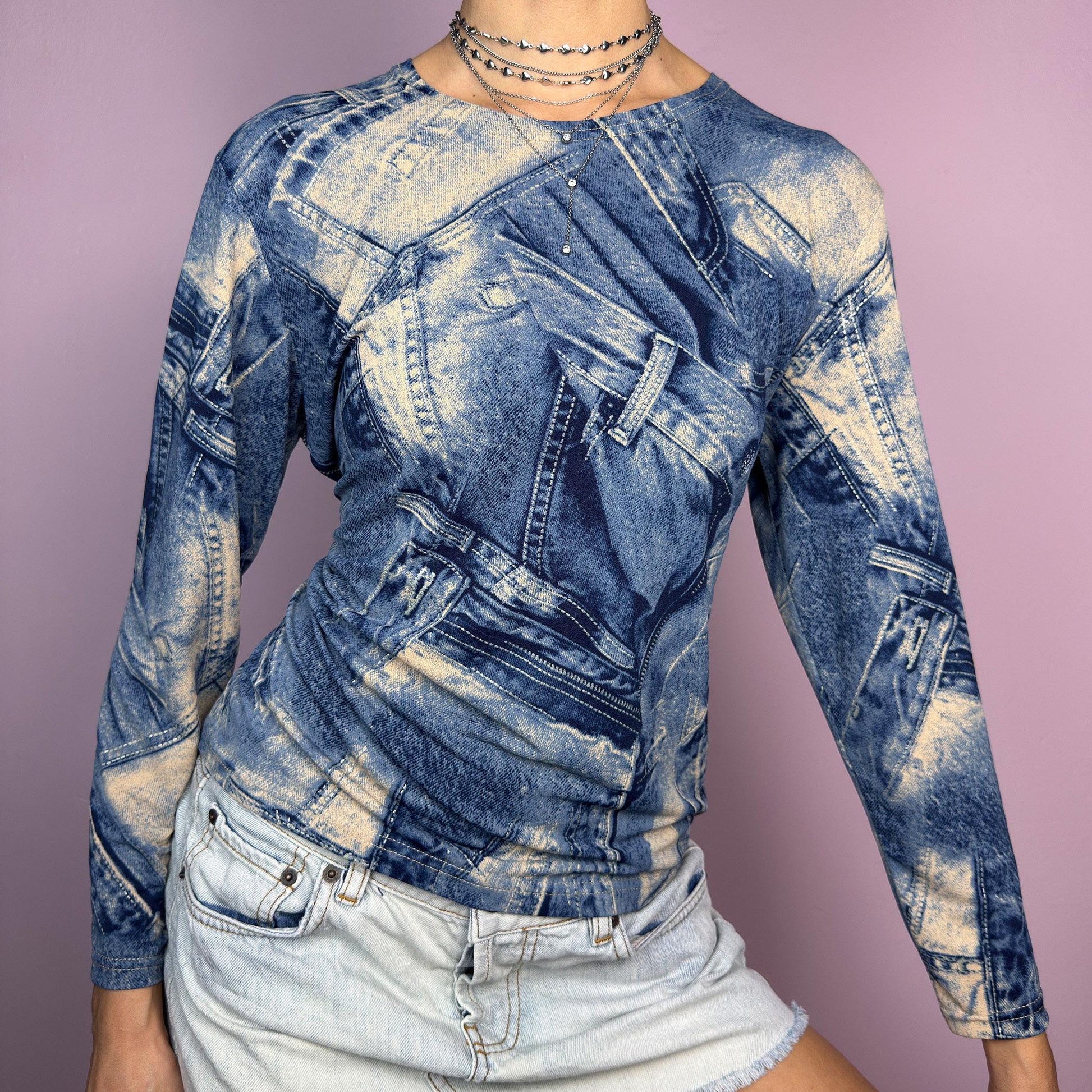 The Y2K Denim Printed Top is a vintage 2000s piece featuring an all-over trompe-l&#39;œil denim print on a stretchy fabric. Designed with long sleeves and a fitted silhouette, this statement top blends classic denim aesthetics with a futuristic vibe. Perfect for casual outfits. adult world shop