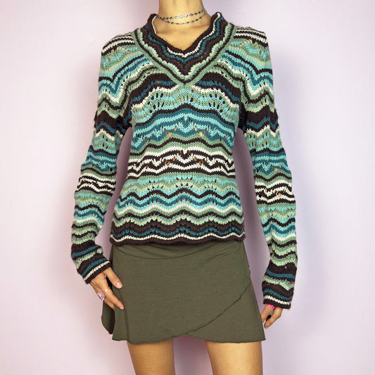 The Y2K Wave Open Knit Sweater is a vintage 2000s pullover featuring a mesmerizing wave-like pattern in shades of teal, brown and beige. This cozy sweater showcases a textured open-knit design, long sleeves, and a v-neckline. Perfect for autumn casual or layered outfits. Great vintage condition.