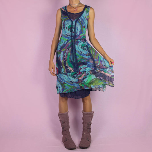 The Y2K Art Print Mesh Dress is a vintage 2000s piece featuring a flowing A-line silhouette with an abstract, artistic print in vibrant tones of blue, green, and purple. Crafted from lightweight, semi-sheer mesh fabric, it offers a layered design
