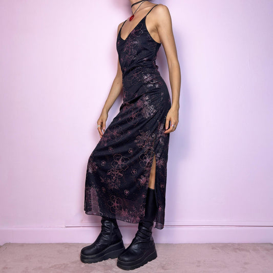 The Y2K Black Glitter Midi Dress is a rare 2000s dress featuring a delicate pink glitter floral pattern on a sheer black mesh overlay with a soft lining beneath. This midi-length piece includes skinny spaghetti straps, a deep V neckline, and a side slits for added movement. The open lace-up back detail gives it a sultry edge, perfect for night outs, alt party looks, or romantic goth aesthetics. Fitted silhouette with a flattering drape. Made in France. Excellent vintage condition.