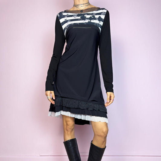 The Y2K Black Ruffle Mini Dress is a vintage 2000s piece with a playful, deconstructed vibe and a bold mix of textures and prints. It features a black stretch body with long sleeves, an abstract striped panel across the chest, a sheer polka-dot neckline detail, and a flared silhouette with a layered ruffle hem combining mesh and mini polka-dot fabrics. Comfortable yet eye-catching, it&#39;s a standout piece for edgy, experimental, or artsy Y2K looks. Great vintage condition.