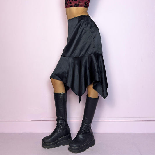 The Y2K Black Satin Asymmetric Skirt is a vintage 2000s stylish piece, featuring a satin-like finish with an asymmetrical handkerchief hemline for a dramatic flair and a size zipper closure. Perfect choice for party nights. Adult World Shop