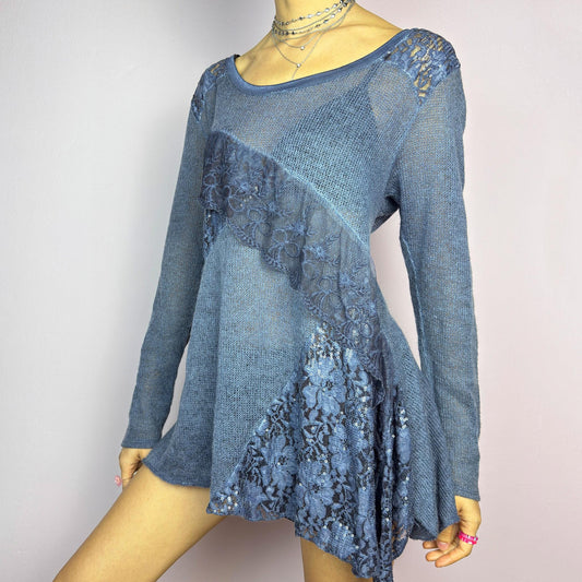 The Y2K Blue Lace Asymmetric Sweater is a vintage 2000s piece featuring a semi-sheer knit design with delicate lace and sequin paneling in an asymmetrical pattern. Designed with a scoop neckline, long sleeves, and a flowy silhouette, this sweater tunic adds a dreamy, romantic touch to any outfit. Perfect for layering in autumn and winter. adult world shop