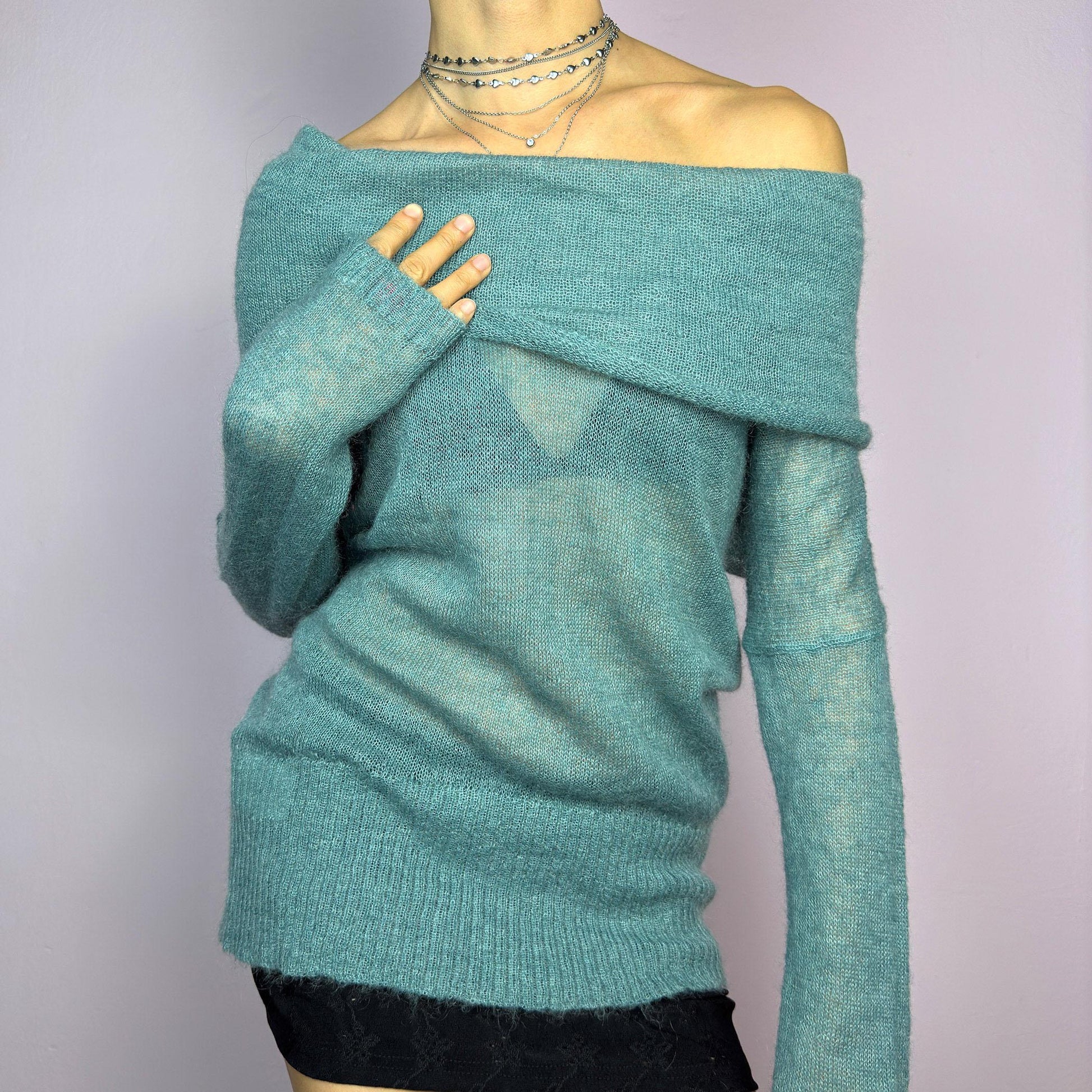 The Y2K Blue Off-Shoulder Sweater is a vintage 2000s cozy and comfy piece made from a mohair, wool, and nylon blend. This soft, semi-sheer sweater features a folded off-shoulder neckline and a muted blue hue. adult world shop