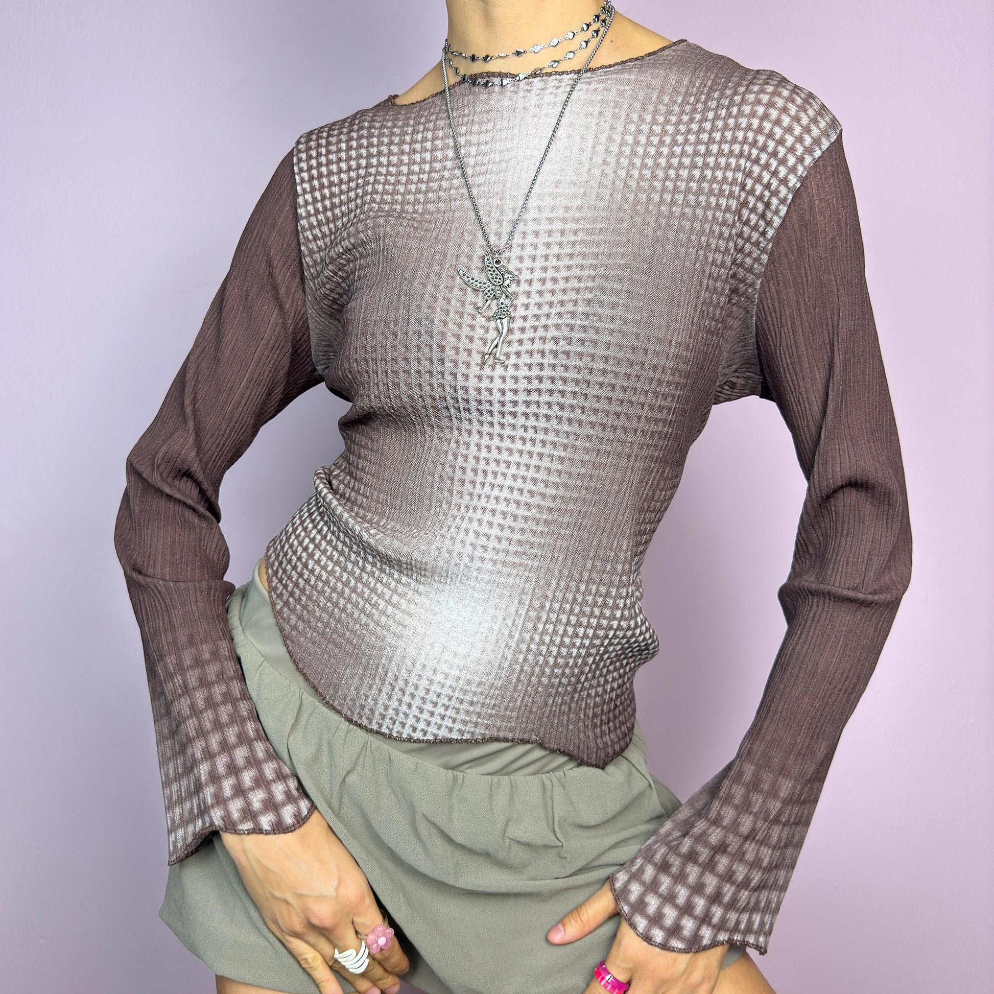 The Y2K Brown Ombre Gradient Top is a vintage 2000s semi-sheer stretchy top featuring a unique ombre gradient print that fades from deep brown to a soft beige. Designed with a subtle asymmetric cut, ribbed texture, and long sleeves, this statement piece adds a futuristic yet earthy touch to casual and streetwear outfits. Perfect for a sleek, edgy look. adult world shop