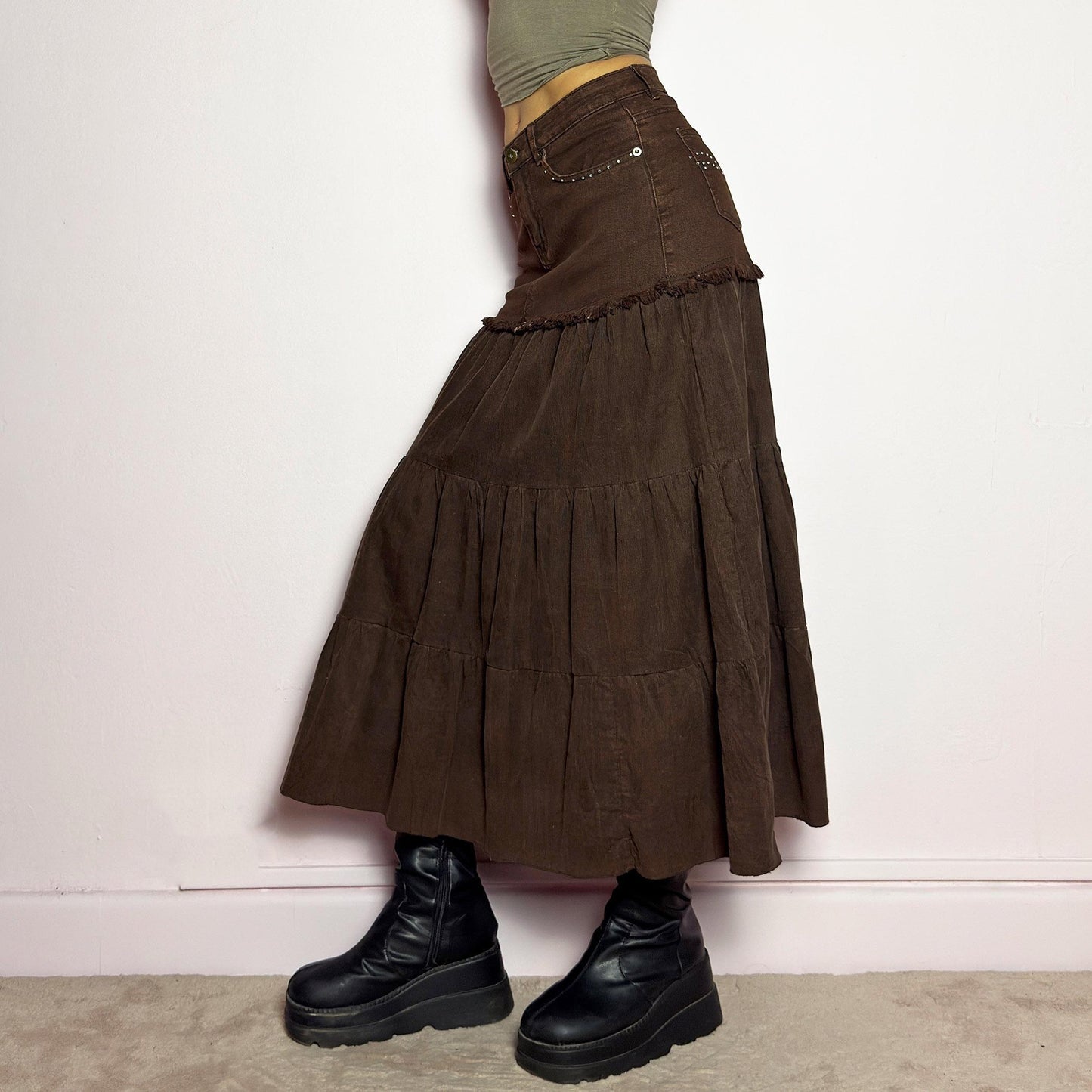 The Y2K Brown Tiered Midi Skirt is a vintage 2000s piece combining denim and soft corduroy for a unique mixed-fabric look. Featuring a stretchy waistband with rhinestone embellishments, pockets and a button-zipper closure, this skirt transitions into flowy tiered corduroy panels for a boho-inspired silhouette. Perfect for casual outfits. adult world shop