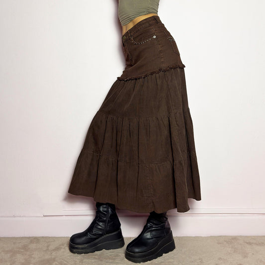 The Y2K Brown Tiered Midi Skirt is a vintage 2000s piece combining denim and soft corduroy for a unique mixed-fabric look. Featuring a stretchy waistband with rhinestone embellishments, pockets and a button-zipper closure, this skirt transitions into flowy tiered corduroy panels for a boho-inspired silhouette. Perfect for casual outfits. adult world shop