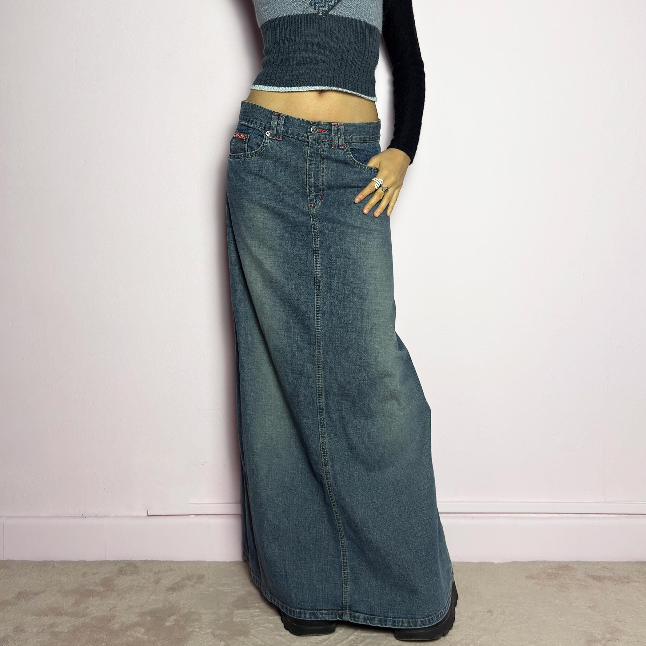 The Y2K Denim Maxi Skirt is a vintage 2000s essential featuring a structured denim fabric in a classic blue wash with subtle fading details. Designed with a mid-rise fit, button and zipper closure, and functional pockets, this skirt offers a sleek yet relaxed silhouette. The back slit adds ease of movement, making it perfect for casual everyday wear. adult world shop