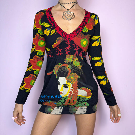 The Y2K Desigual Graphic Print Top is a rare vintage 2000s long sleeve top by Desigual featuring an eclectic mix of prints and bold colors. This artsy piece combines floral motifs, illustrated portraits, and poetic text layered over a stretchy black base. Designed with a deep V-neckline and empire waist for a flattering silhouette. The bottom hem is subtly gathered for a closer fit, giving it a mini dress vibe. Includes hidden side pockets. adult world shop