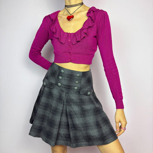 The Y2K Gray Plaid Pleated Mini Skirt is a vintage 2000s essential, featuring a structured pleated design with decorative button details. Made from a thick woven fabric with a black plaid pattern, it is ideal for winter outfits. adult world shop