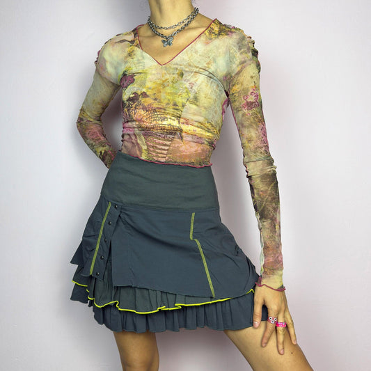 The Y2K Gray Ruffle Mini Skirt is a vintage 2000s statement piece featuring a tiered layered design with yellow contrast stitching details. Designed with a high-waist fit, it includes a side zipper closure. adult world shop