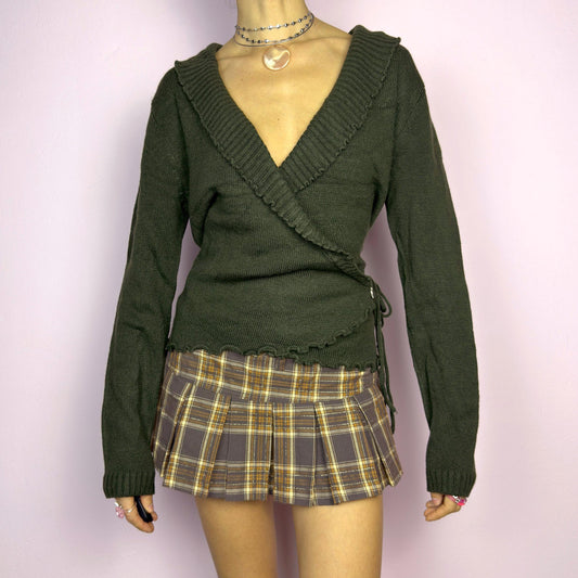 The Y2K Green Wrap Tie Cardigan is a vintage 2000s piece, featuring a deep V-neck, wrap-front design with tie closure, and subtle ruffle details along the neckline. Made from a soft mohair and acrylic blend, this cardigan has a rich forest green tone, perfect for layering over casual or dressed-up outfits. adult world shop