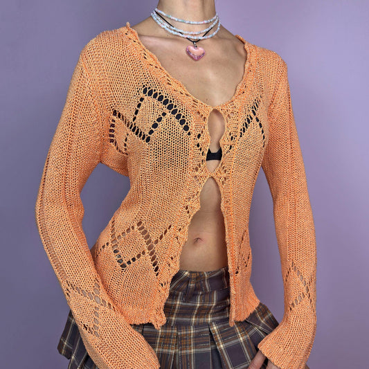 The Y2K Orange Open Knit Sweater is a feminine vintage 2000s piece, ideal for spring layering. Featuring a delicate diamond-shaped open-knit pattern, a deep V-neckline and long sleeves. Perfect for casual everyday outfits. adult world shop