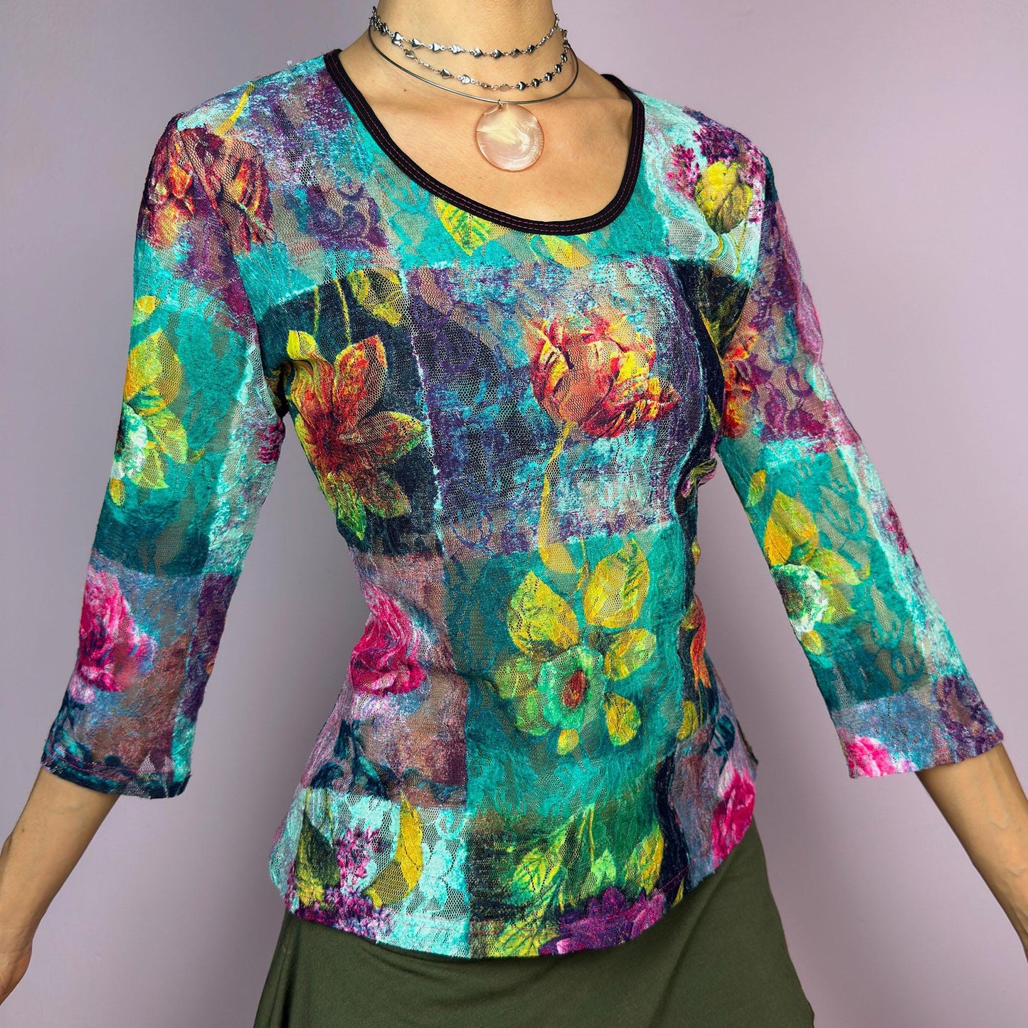 The Y2K Painting Lace Mesh Top is a vintage 2000s artistic statement piece. Featuring a semi-sheer lace fabric adorned with a bold, vibrant floral pattern resembling a painterly masterpiece, a scoop neckline and 3/4 sleeves. adult world shop