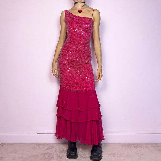 The Y2K Pink Rhinestone Ruffle Dress is a dazzling statement piece from the 2000s. Designed with a bold asymmetrical neckline and one-shoulder spaghetti strap, the fitted upper body is fully adorned with shimmering rhinestones. The bottom features a dreamy layered ruffle skirt that creates a mermaid silhouette. Made from a lightweight, flowy fabric with a side zipper closure for easy wear. Perfect for special occasions, early 2000s glam, or standout party looks.