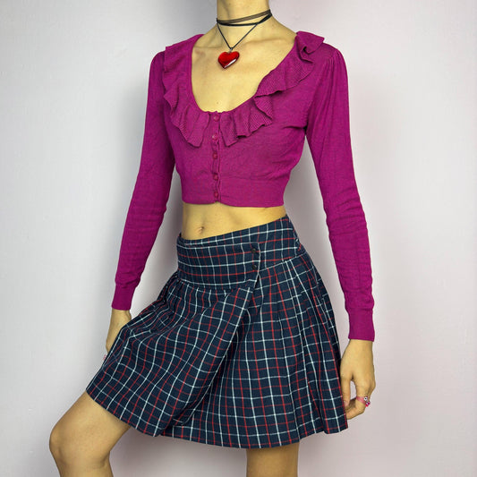 The Y2K Plaid Pleated Wrap Mini Skirt is a vintage 2000s piece featuring a wrap-style waistband with snap button details. Made from a plaid fabric in navy blue tones, it has structured pleats that create a classic silhouette. adult world shop