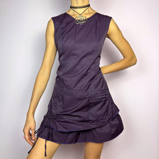 The Y2K Purple Layered Mini Dress is a vintage 2000s sleeveless dress in a deep purple hue, featuring a structured, layered silhouette, a side pocket, an adjustable drawstring ruched detail on the side for a customizable fit. adult world shop