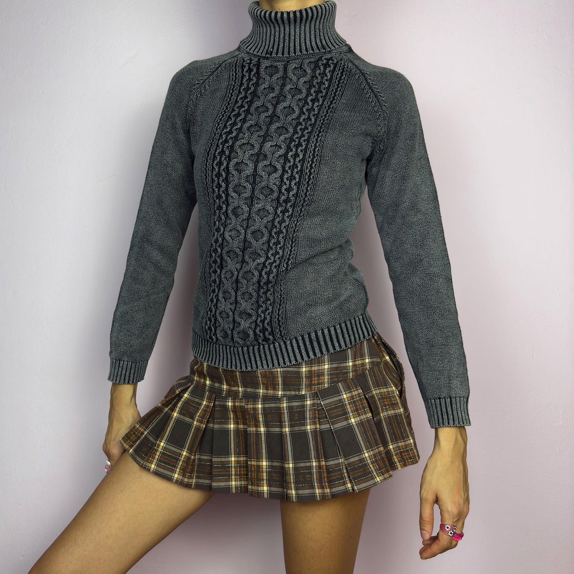The Y2K Washed Gray Turtleneck Sweater is a vintage 2000s piece, featuring a slightly faded gray tone for a worn-in, effortless look. Designed with an intricate cable knit pattern on the front, ribbed cuffs, and a thick turtleneck, it offers both warmth and style. Ideal for preppy, academia, or casual winter outfits. adult world shop