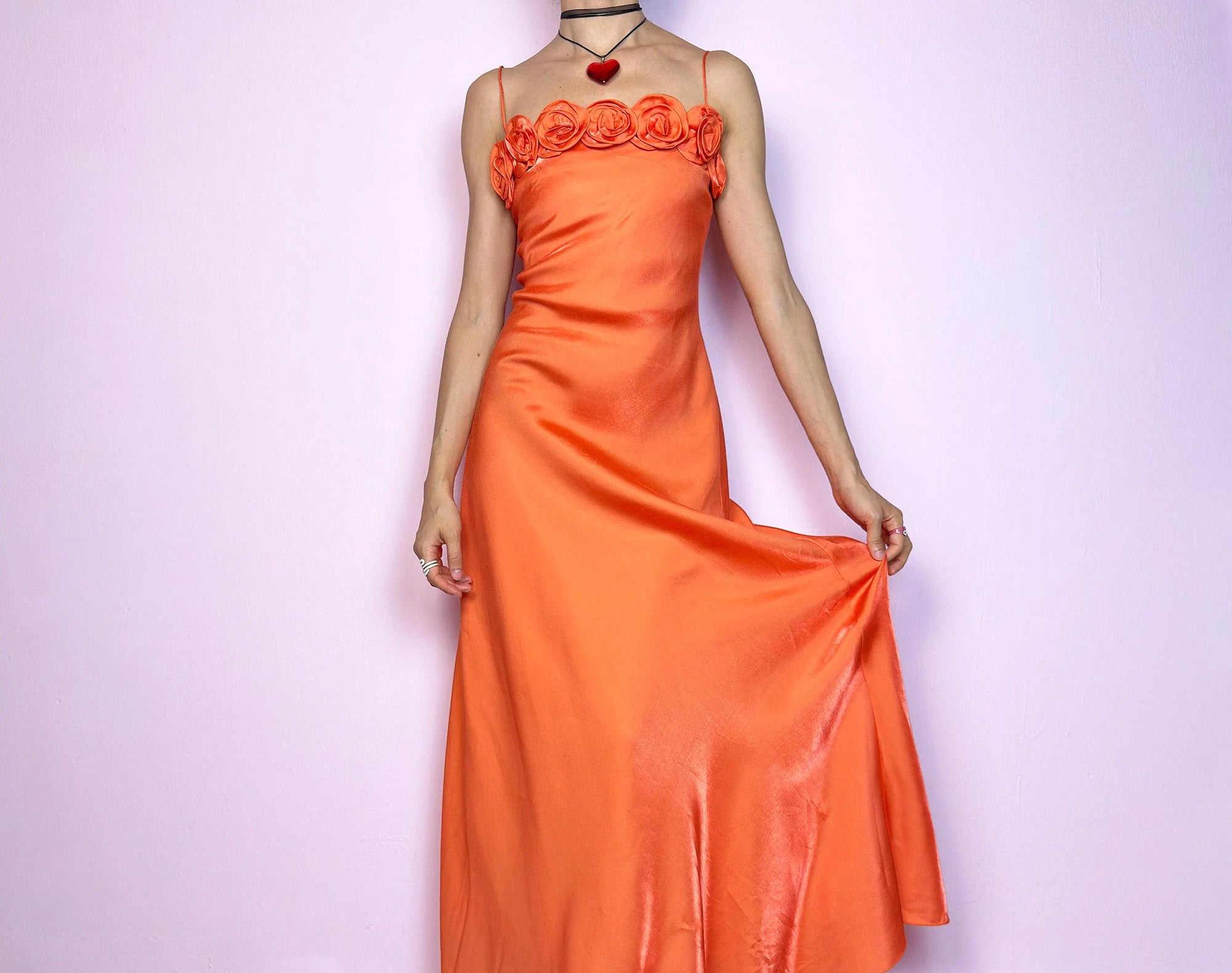 The Y2K Orange Rose Maxi Dress is a stunning 2000s satin-style slip dress featuring a vibrant orange tone and romantic rose appliqué details along the bust. Designed with skinny spaghetti straps and a softly flared maxi silhouette that drapes beautifully. Lightweight and glossy with a smooth sheen – a perfect statement piece for summer weddings, garden parties, or dreamy fairycore evenings. Made in France.