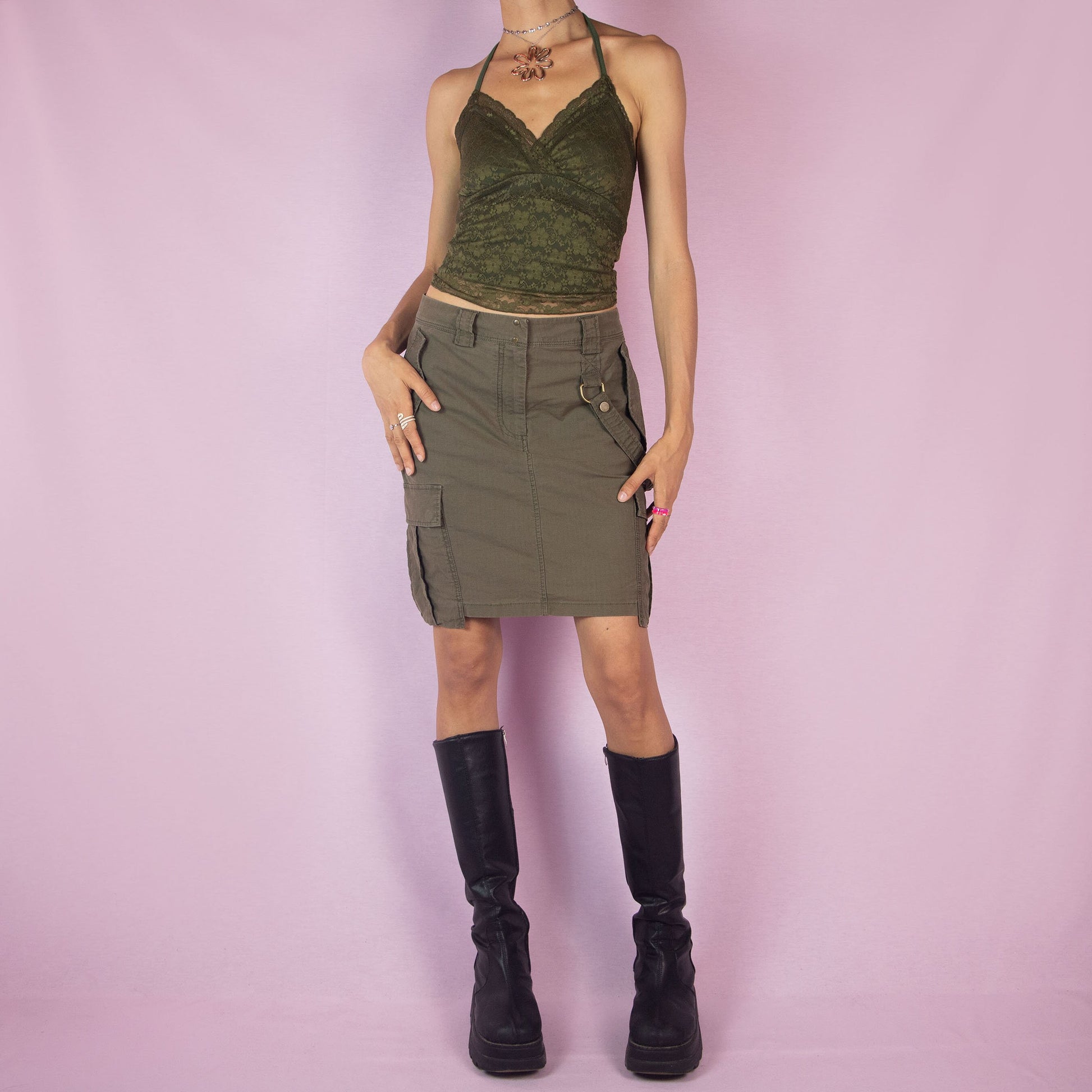 The Y2K Diesel Khaki Cargo Skirt is a vintage 2000s green mini skirt featuring a military-inspired design with multiple pockets, belt loops, and a front zipper closure.