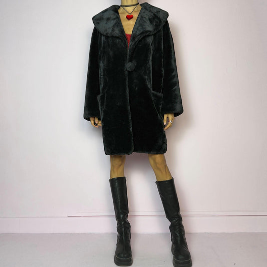 The Vintage 90s Black Faux Fur Coat showcases a faux fur material for a sophisticated and cozy winter style. It features a plush oversized collar, a chic fabric-covered button closure, and pockets. Perfect for winter outings or evening events.